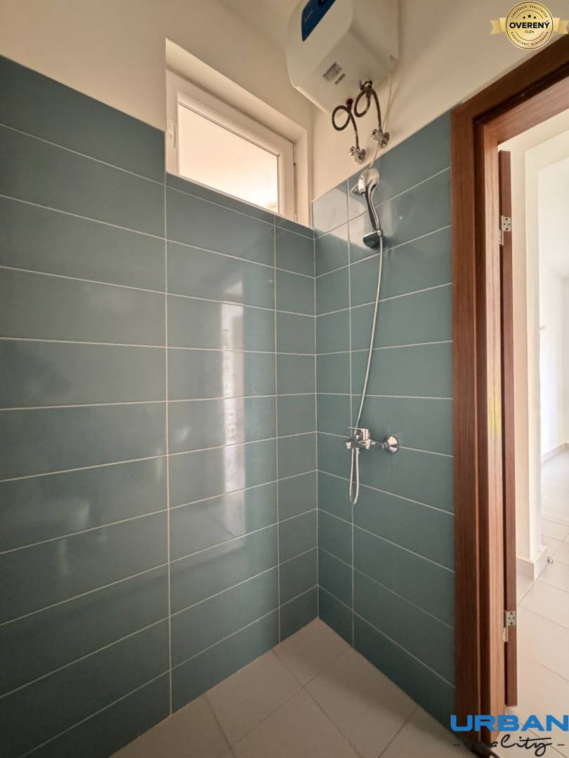 Kúpeľňa s obkladom z modrých kachličiek a sprchou v 2-izbovom byte.