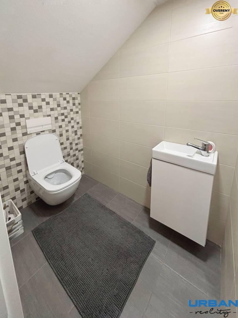 Kúpeľňa v 3-izbovom byte s geometrickým obkladom a šikmým stropom.