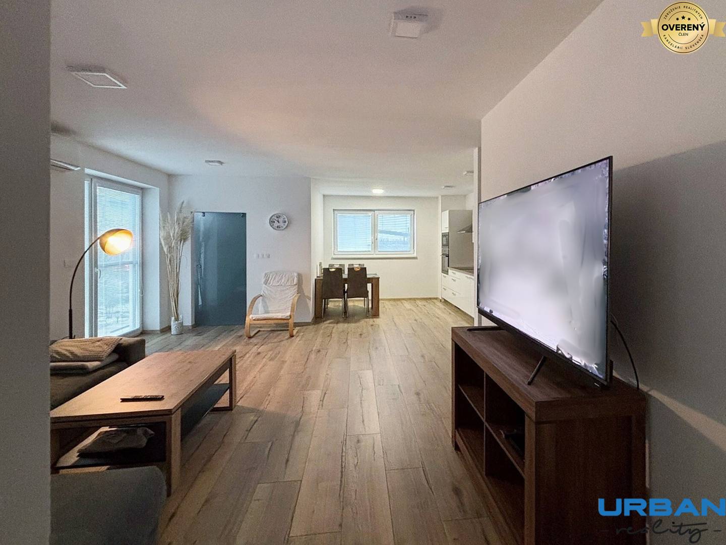 Obývacia izba v 3-izbovom byte so stolom, televízorom a podlahou s dreveným dekorom.