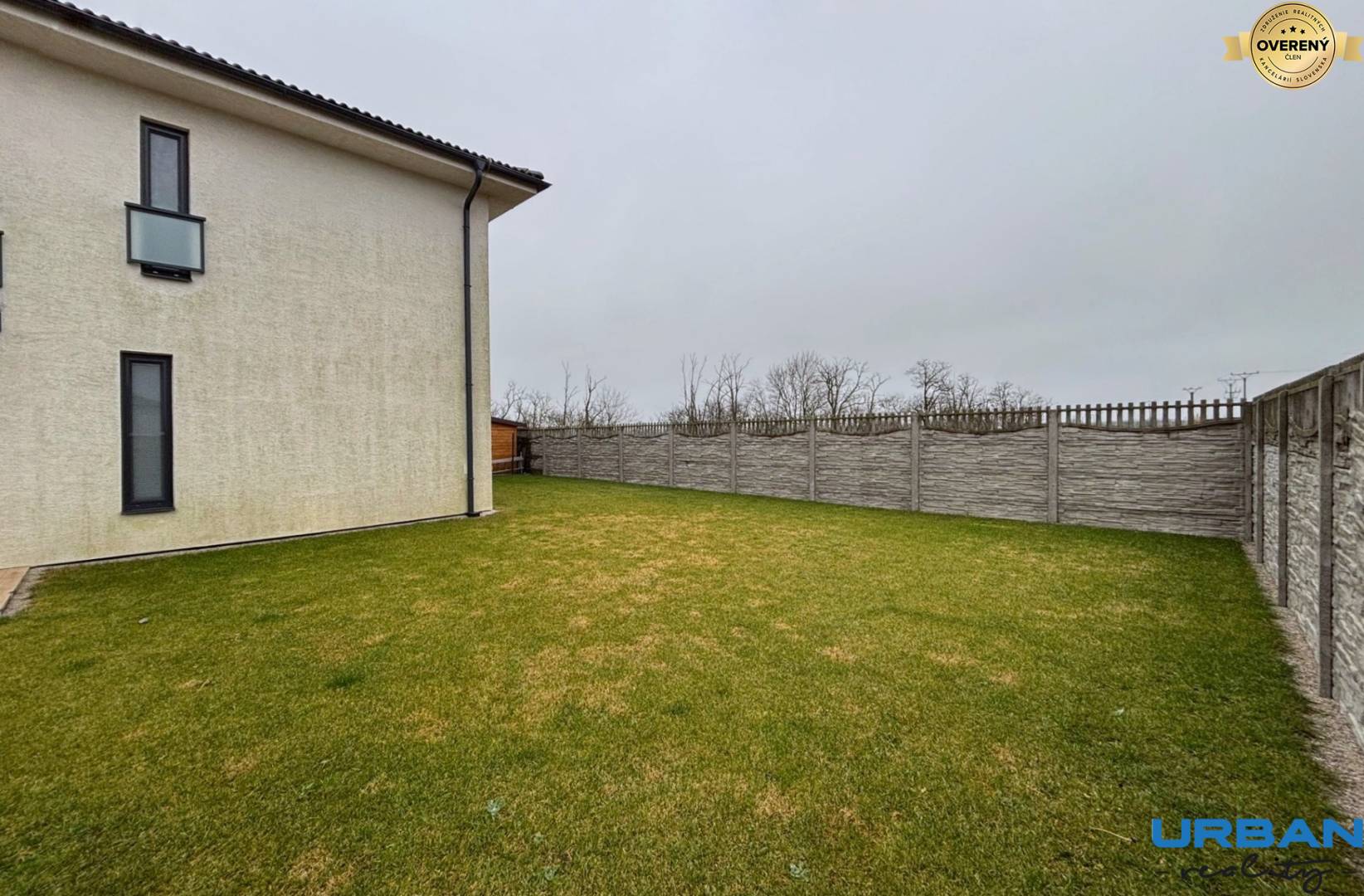 Exteriér 3-izbového bytu v Kráľoviankach s trávnikom a betónovým plotom.