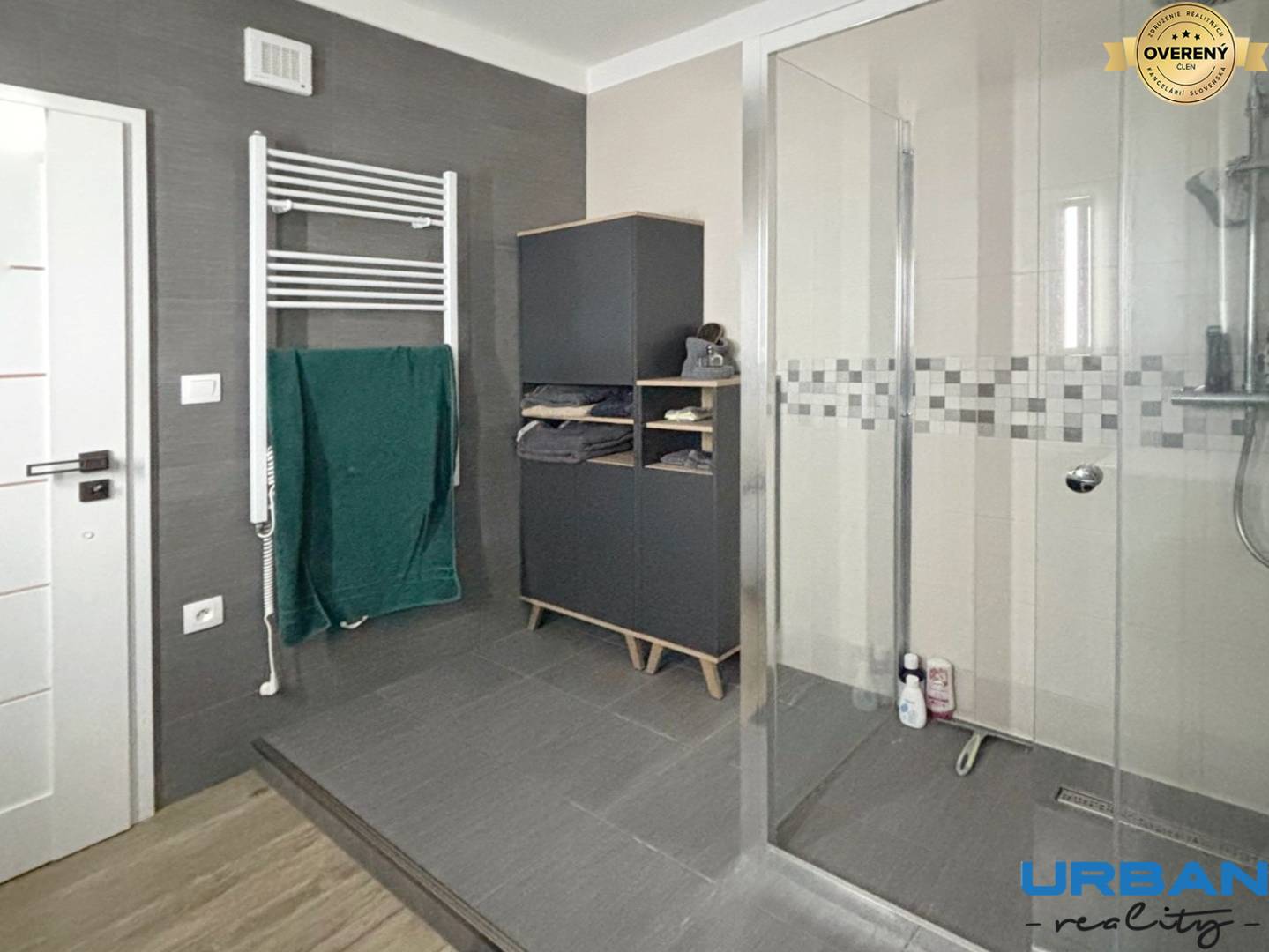 Kúpeľňa v 3-izbovom byte s moderným sprchovacím kútom a tmavým nábytkom.