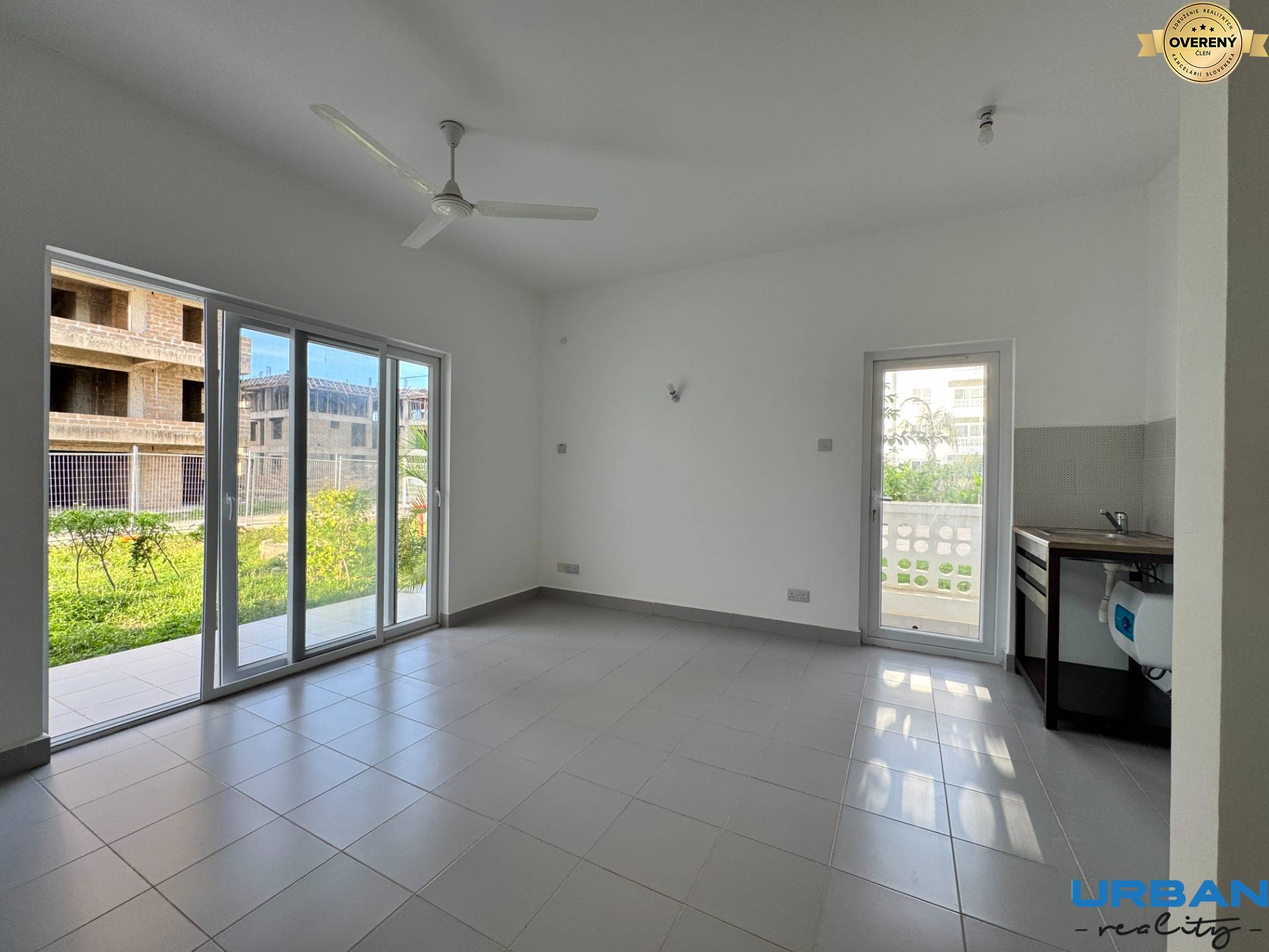 Izba s veľkými oknami, bielym stropom a kachličkovou podlahou v 2-izbovom byte.