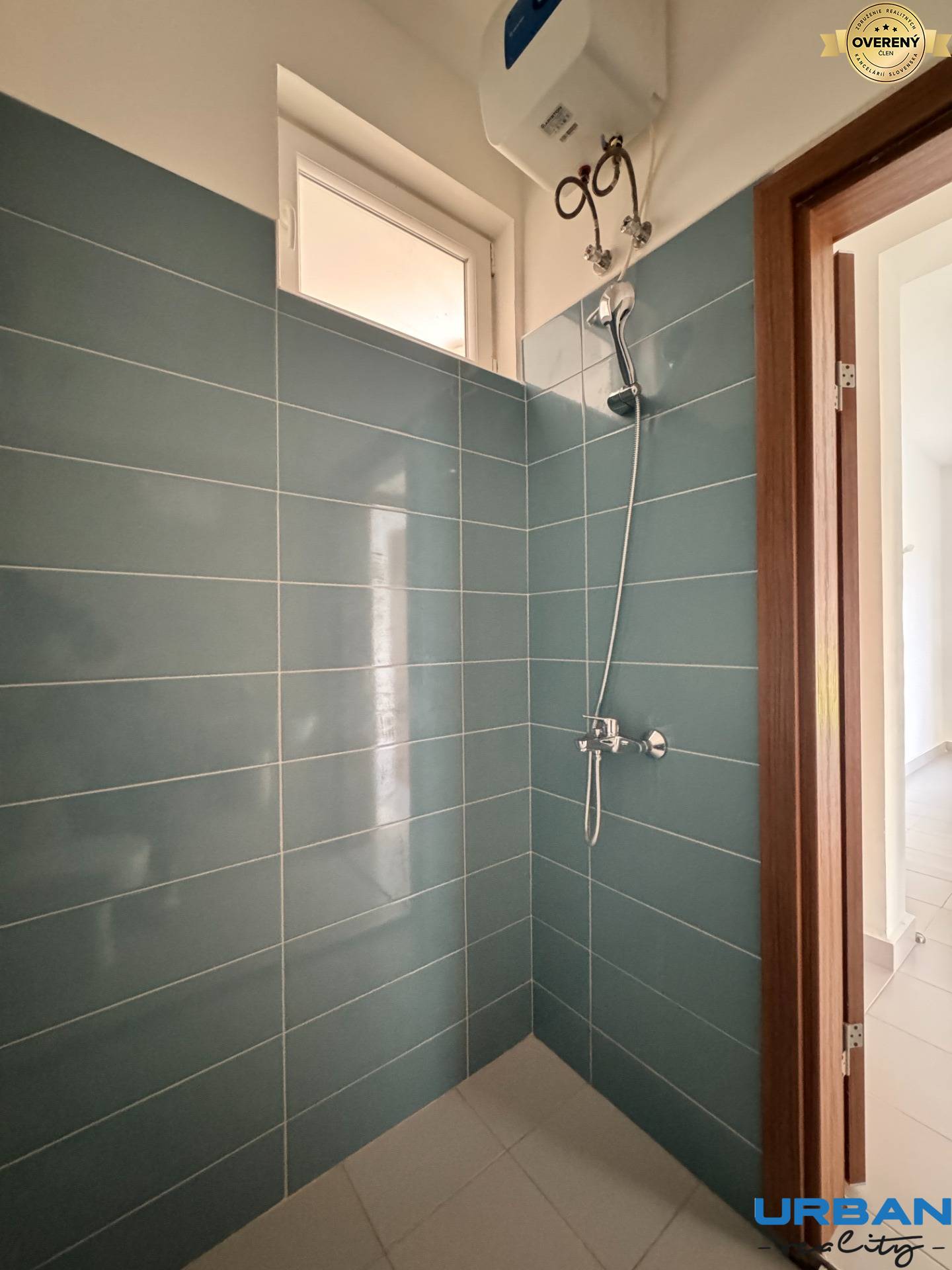 Kúpeľňa s obkladom z modrých kachličiek a sprchou v 2-izbovom byte.